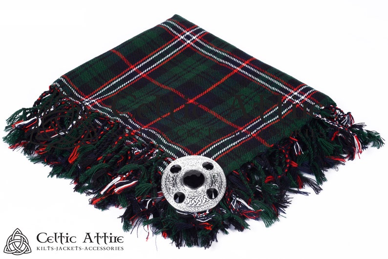 May include: A green, red, and white tartan kilt pin with a silver Celtic knot design. The pin is on a green, red, and white kilt.