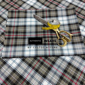 K&ouml;nnte beinhalten: Karomuster Stoff in Grau, Schwarz, Wei&szlig; und Rot, mit einer goldenen Schere und einem gelben Ma&szlig;band. Der Text "AUTHENTIC WEAVE BY CELTIC ATTIRE" ist zu sehen. Geeignet f&uuml;r N&auml;hprojekte.