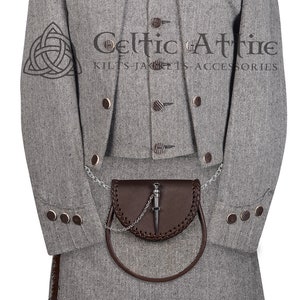 May include: A grey herringbone kilt with a brown leather sporran and a silver chain. The kilt is paired with a matching grey jacket with a mandarin collar and brown buttons. The jacket has a Celtic knot design on the sleeve. The text "Celtic Attire Kilts Jackets Accessories" is printed on the jacket.