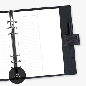 May include: A black A5 size planner with lined white paper. The planner has a silver metal binder and a black leather cover with a strap closure. The text "A5 SIZE" is printed on a black circle.