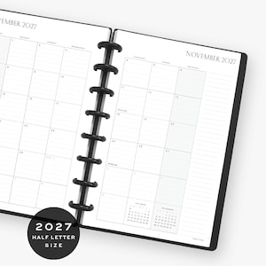 May include: A disc-bound planner open to a monthly calendar view for November 2027. The white pages feature black grid lines, headers for days of the week, and a small reference calendar for October and December. A black plastic spine holds the pages.