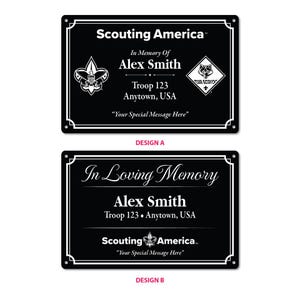 May include: Two rectangular black memorial plaques with white text and borders. Design A features Scouting America, In Memory Of Alex Smith, Troop 123, Anytown, USA, and Your Special Message Here. Design B displays In Loving Memory, Alex Smith, Troop 123, Anytown, USA, Scouting America, and Your Special Message Here.