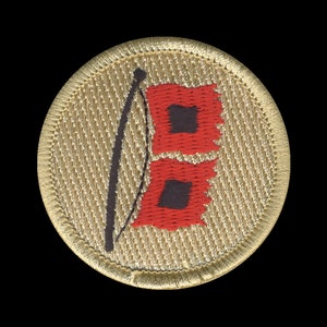 May include: Embroidered patch with a tan background and a gold border. The patch features a black pole with two red flags, each with a black square in the center. The flags are slightly tattered, giving a vintage look.