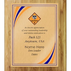 May include: A wooden plaque with a gold background and blue and orange accents. The plaque features the Cub Scouts logo and text that reads "In sincere appreciation of your outstanding leadership and tireless dedication to Pack 123 Anytown, USA Name Here Den Leader Dates".