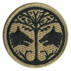 May include: A round, tan-colored patch with a black embroidered design of a tree with two birds on either side. The tree has a stylized, intricate design.