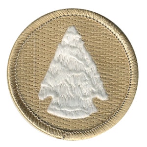 May include: A tan embroidered patch with a white arrowhead design.