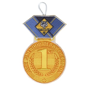 May include: Embroidered gold-colored patch with a blue and gold top section. The patch reads "Pack Pine Wood Derby Champion" and features a large "1st" in the center. A white string is attached for hanging.