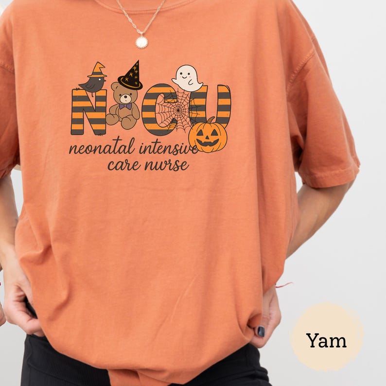 Pu&ograve; includere: T-shirt arancione con un design a tema Halloween. Il design include le lettere "NICU" con un cappello da strega, un orsacchiotto, un fantasma, una ragnatela e una zucca. Il testo "neonatal intensive care nurse" &egrave; sotto.