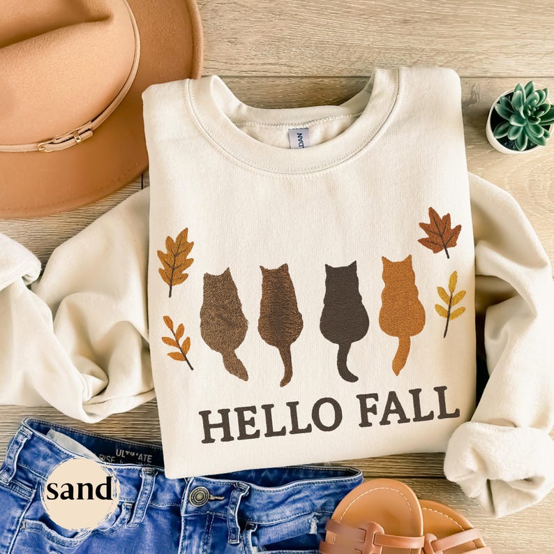 Embroidered cats with “Hello Fall” text and autumn leaves design.