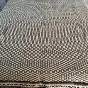 May include: A white and brown woven blanket with a fringe border. The blanket has a diamond pattern.