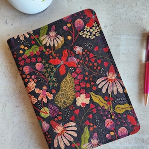May include: A black cork notebook cover with a floral pattern featuring red, pink, yellow, and green flowers. The cover has a stitched edge.