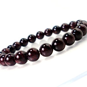 May include: A dark red gemstone bracelet with round beads.