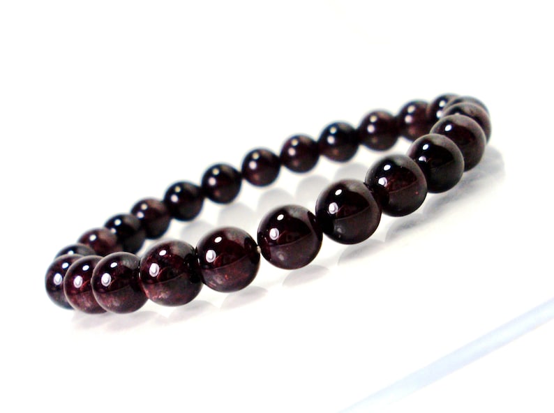 May include: A dark red gemstone bracelet with round beads.