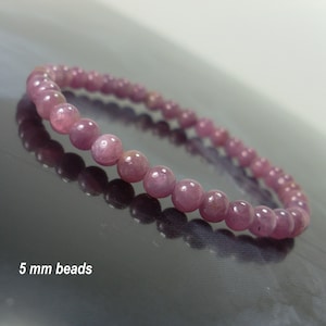 Op de afbeelding: Een roze edelsteen armband met 5 mm kralen. De armband is gemaakt van ronde, gladde kralen die aan elkaar geregen zijn op een doorzichtig elastiek.
