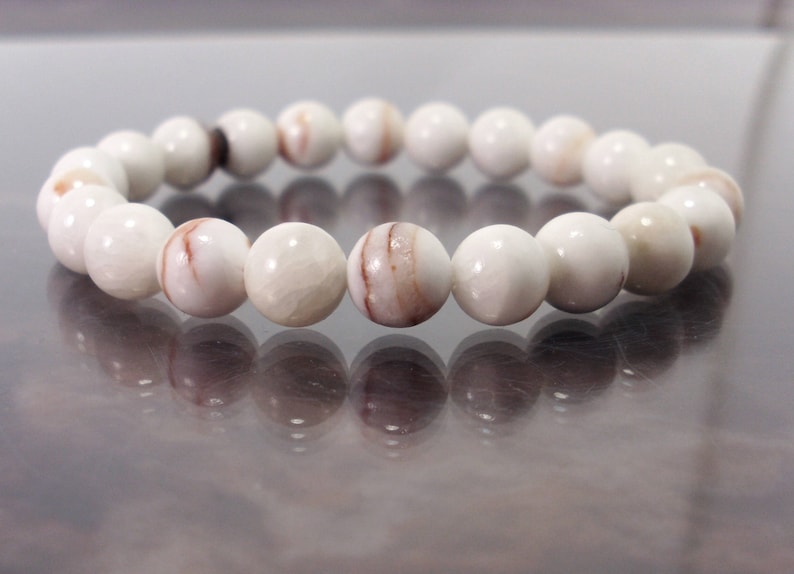 K&ouml;nnte beinhalten: Ein wei&szlig;es Armband mit braunen Streifen aus runden Perlen.