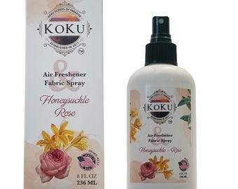 May include: A white bottle with a black spray nozzle and a label that reads "KOKU Air Freshener Fabric Spray Honeysuckle-Rose 8 FL OZ 236 ML". The bottle is next to a box with the same label and a picture of honeysuckle and roses.