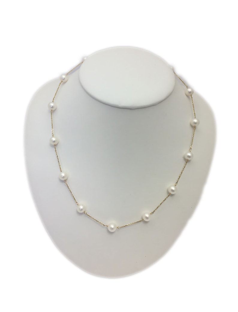Puede incluir: Un collar de cadena dorada con perlas blancas. El collar se muestra en un busto de maniqu&iacute; blanco.