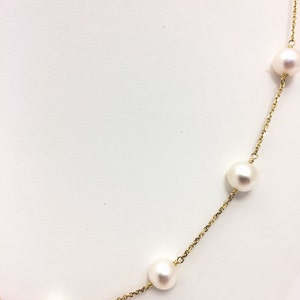 Puede incluir: Un collar de cadena de oro con perlas blancas. Las perlas est&aacute;n espaciadas uniformemente a lo largo de la cadena.