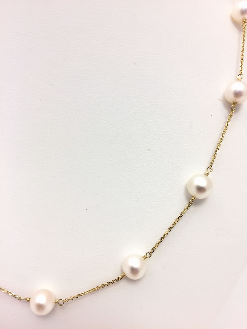 Puede incluir: Un collar de cadena de oro con perlas blancas. Las perlas est&aacute;n espaciadas uniformemente a lo largo de la cadena.
