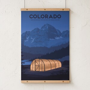 May include: A poster featuring a nighttime landscape of Colorado with a mountain range and a greenhouse. The word "COLORADO" is at the top, with the text "ENLIGHTENING THE NATION ON LEGALIZATION" below it. The poster is held by wooden bars.