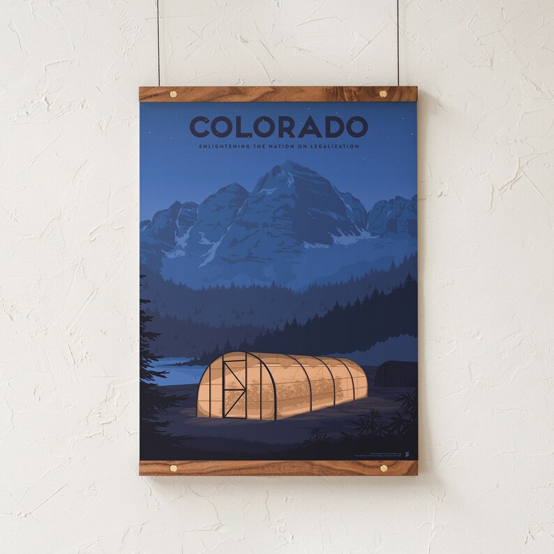 May include: A framed poster with a wooden frame. The poster features a nighttime landscape with mountains, trees, and a greenhouse. The word "COLORADO" is at the top, with the text "Enlightening the Nation on Legalization" below.