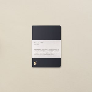 Può includere: Un diario con copertina rigida blu scuro con il testo "GOLDLEAF Grow Journal" e una descrizione delle caratteristiche del diario. Il diario ha una "g" dorata sulla copertina.