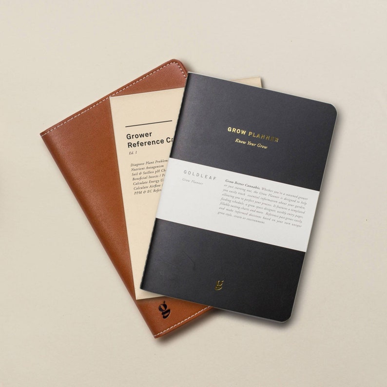 May include: A black and brown leather-bound journal with the title "Grow Planner: Know Your Grow" and the text "Grow Better Cannabis" on the cover. The journal is open to reveal a white page with text about growing cannabis.