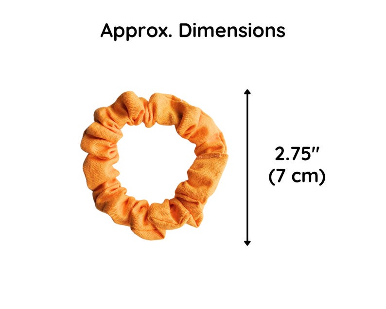 May include: A bright orange fabric scrunchie with a gathered, ruffled texture. The text 'Approx. Dimensions' appears above the object, and a vertical arrow indicates a measurement of 2.75 inches, which is equivalent to 7 cm in total diameter.