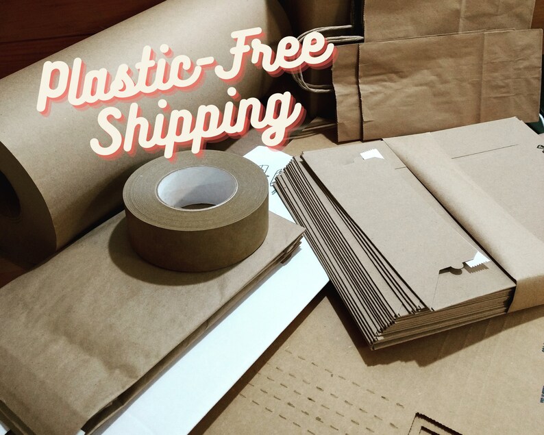 May include: A collection of brown kraft paper supplies including a large roll, a roll of adhesive tape, and stacks of flat paper bags. The text Plastic-Free Shipping is overlaid in a white font with a red outline across the top of the items.