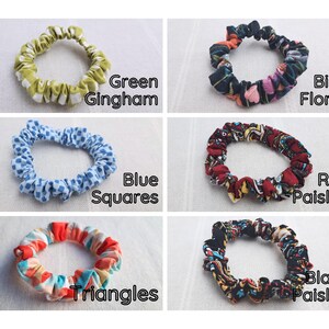 May include: Six fabric hair scrunchies arranged in a grid. Patterns include green gingham, bird floral, blue squares, red paisley, multi-colored triangles, and black paisley. Each scrunchie is labeled with its respective pattern name in black text.