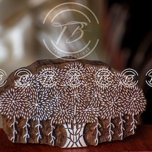 May include: A carved wooden block with a floral tree design. The block is brown with white accents, and the design features stylized trees with detailed floral patterns. The Tahli Boutique logo is visible in the background.
