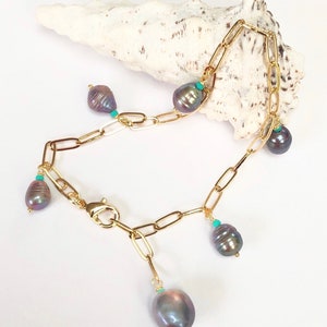 May include: A gold chain bracelet with five dark gray pearl charms and turquoise accents.