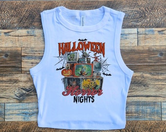 May include: A white sleeveless crop top with a graphic print of a vintage television set with a Halloween theme. The graphic includes the text "Halloween Horror Nights".