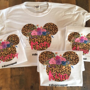 May include: Four white t-shirts with a leopard print Mickey Mouse head design with floral accents. The shirts have the words "Mommy", "Kira", and "#disneysquad" printed on them.
