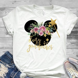 May include: White t-shirt with a black Mickey Mouse head silhouette with floral accents and gold glitter text that reads "Fairy godmother".