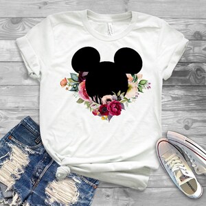 May include: White t-shirt with a black silhouette of Mickey Mouse's head surrounded by a floral wreath with pink, red, and white flowers.