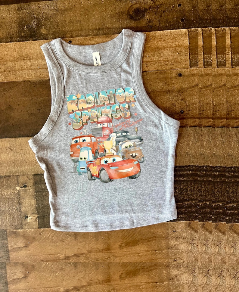 May include: Gray tank top with a graphic of the Cars characters from the movie Cars. The graphic includes the text "Radiator Springs" and features Lightning McQueen, Mater, and other characters.