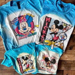 Puede incluir: Cuatro camisetas azules con dise&ntilde;os salpicados de lej&iacute;a con Mickey Mouse y Minnie Mouse. Las camisetas tienen diferentes dise&ntilde;os, incluyendo Mickey Mouse y sus amigos, Mickey Mouse con gafas de sol, Minnie Mouse y Mickey Mouse con Donald Duck y Goofy.