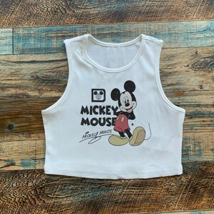 May include: White sleeveless crop top with a black and white image of Mickey Mouse and the text "Mickey Mouse" in black.