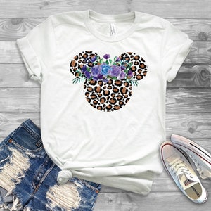 May include: White t-shirt with a leopard print Mickey Mouse head design with purple flowers.