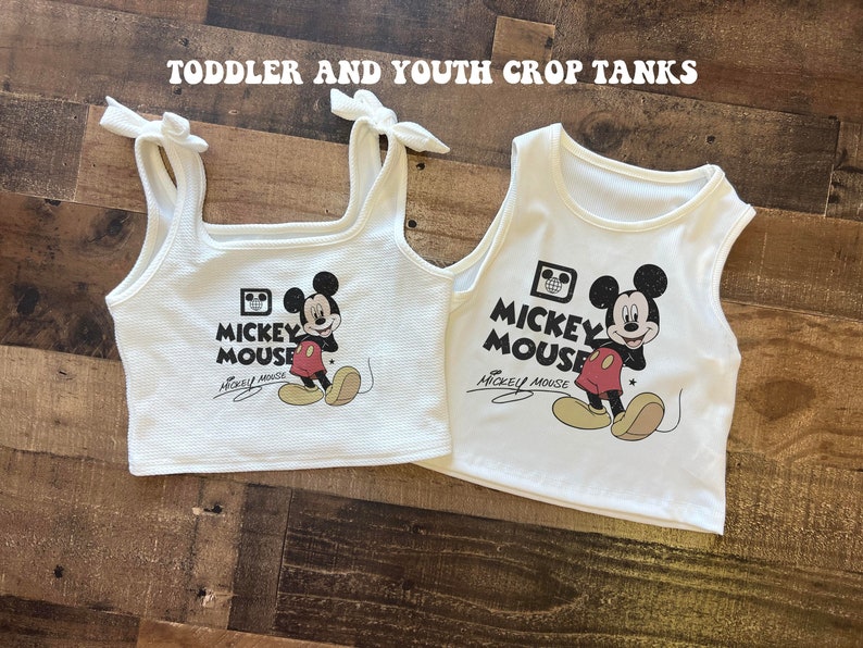 May include: Two white crop tank tops with a Mickey Mouse graphic and the text "Mickey Mouse" printed on the front. The tops are made of a soft, stretchy material and have a relaxed fit.