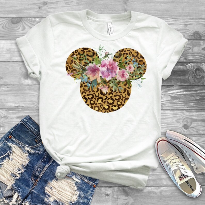 May include: White t-shirt with a floral design in a leopard print Mickey Mouse silhouette.