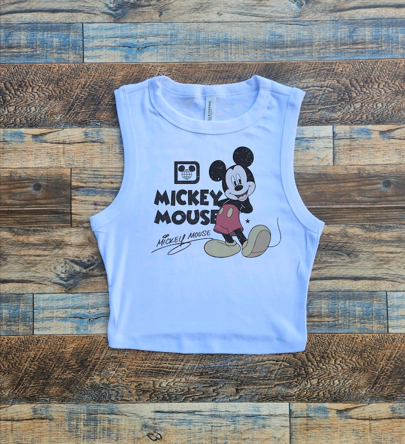 May include: White sleeveless crop top with a vintage Mickey Mouse graphic and the text "Mickey Mouse" in black lettering.