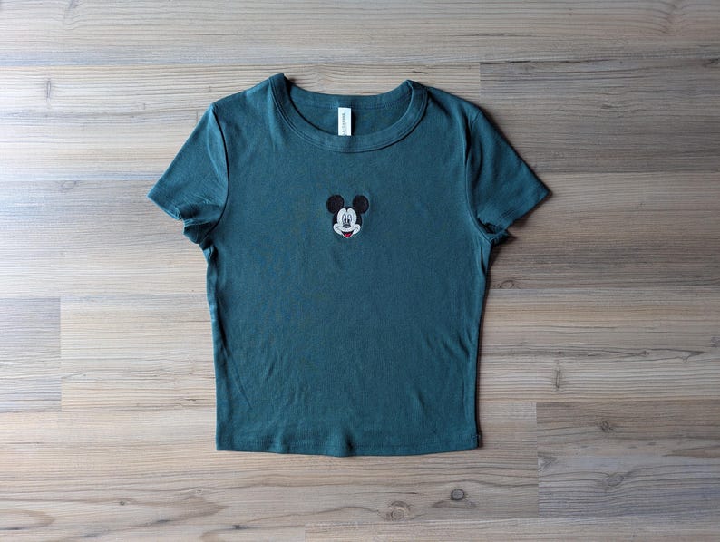 May include: A white ceramic mug with a black handle and the text "But First, Coffee" in a bold, black font. The mug is set against a blurred background, suggesting a cozy setting. The mug appears to be approximately 4 inches tall.