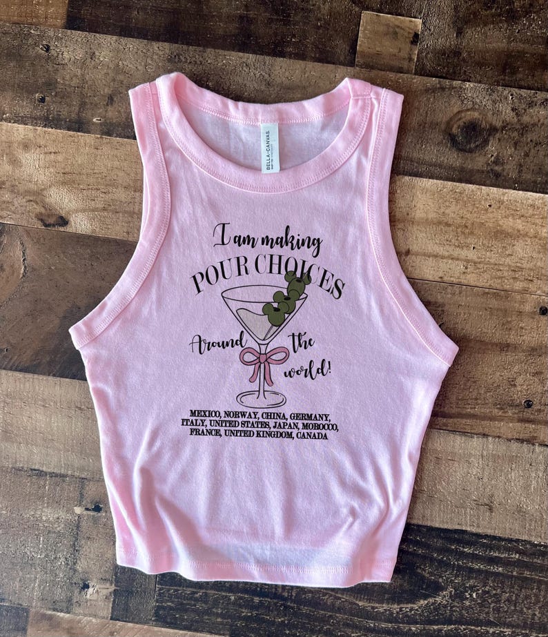 Puede incluir: Una camiseta sin mangas rosa claro de Bella + Canvas con el texto "I am making POUR CHOICES around the world!" y un gr&aacute;fico de copa de martini. La parte inferior de la camisa enumera varios pa&iacute;ses.