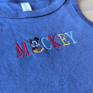 May include: A white ceramic mug with a black handle and the text "But First, Coffee" in a handwritten style. The mug is on a white surface. The mug is 4 inches tall.