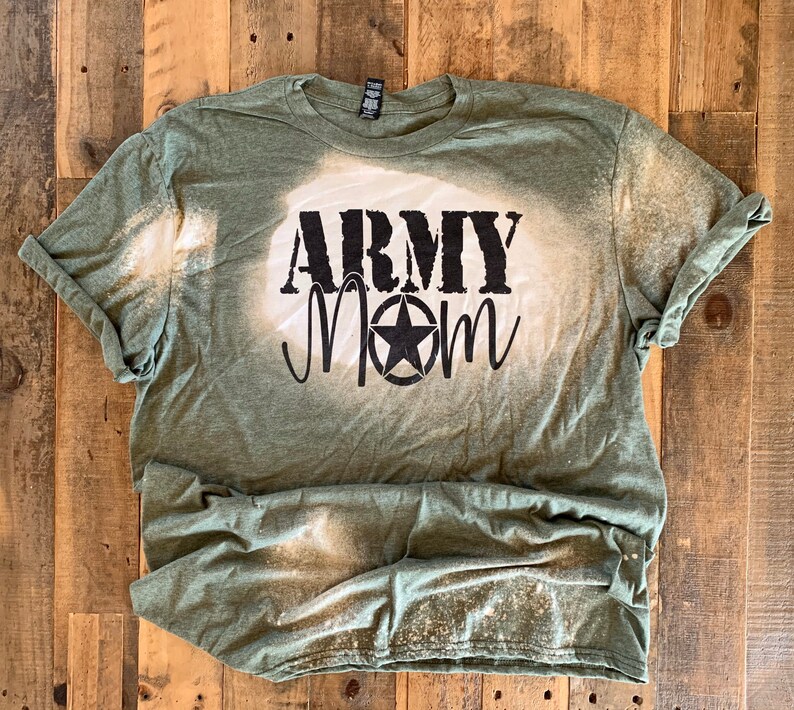 May include: A green t-shirt with a bleach-splattered design. The shirt has the words "Army Mom" printed in black with a star.