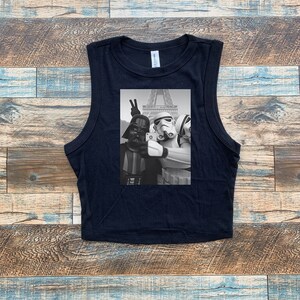 May include: Black sleeveless crop top with a graphic print of Darth Vader, a Stormtrooper, and another Stormtrooper taking a selfie in front of the Eiffel Tower.