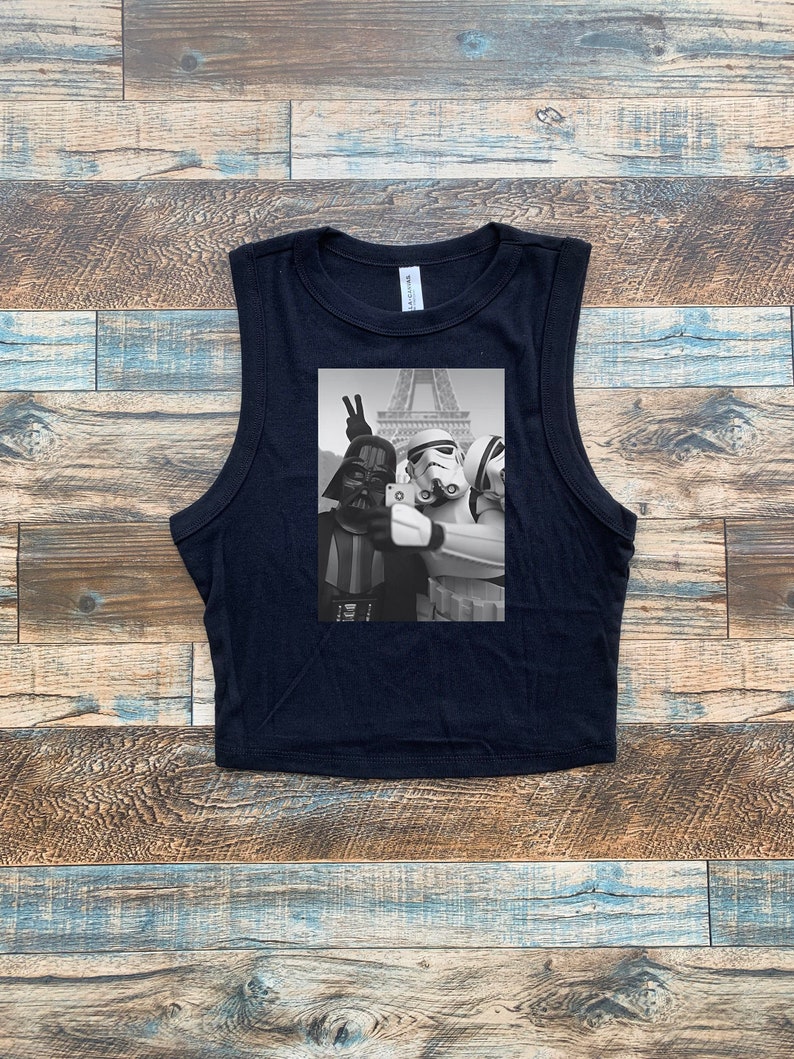May include: Black sleeveless crop top with a graphic print of Darth Vader, a Stormtrooper, and another Stormtrooper taking a selfie in front of the Eiffel Tower.