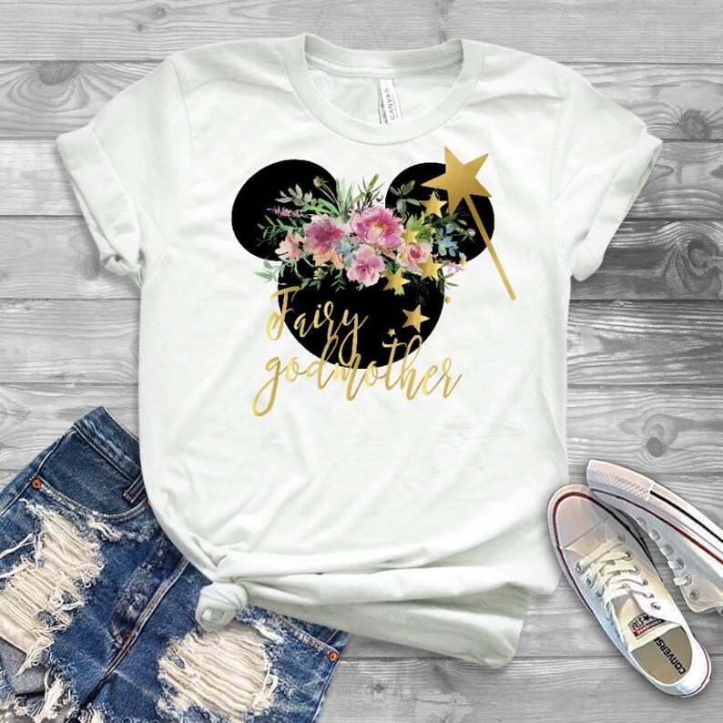 May include: White t-shirt with a black Mickey Mouse head silhouette with floral accents and gold glitter text that reads "Fairy godmother".